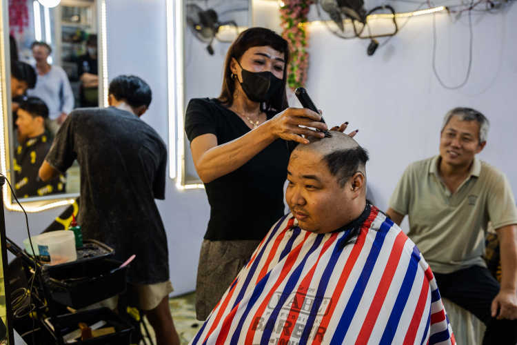 A hairdressers cut the hair of the Chinese worker on the roadside in front of the smelter after their shift in Konawe Regency, Central Sulawesi, Indonesia on June 8, 2024.