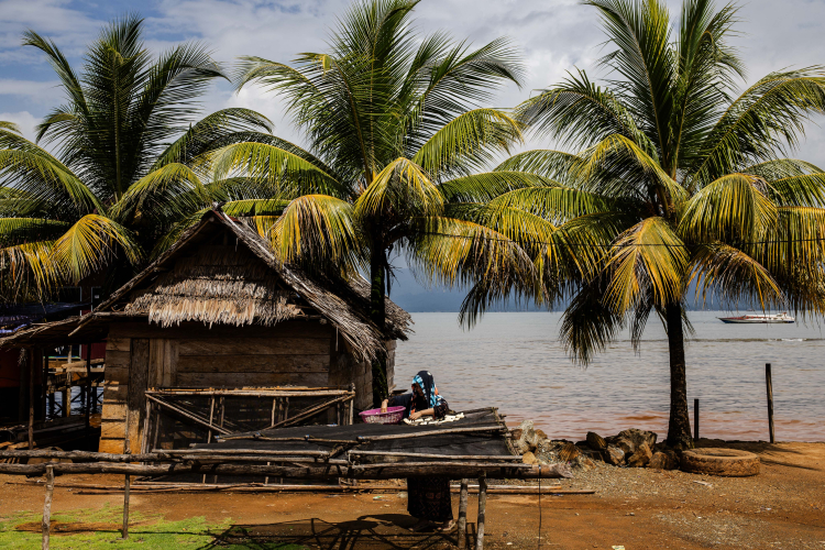 A woman dries banana in the sun next to a home in the area of sea waters contaminated by a nickel mine at Mandiodo village on June 9, 2024 in North Konawe, Southeast Sulawesi, Indonesia.