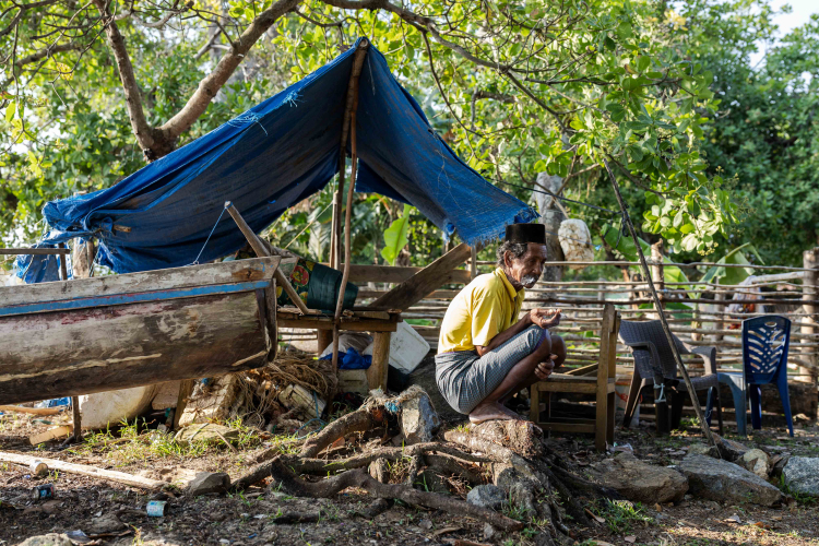 Alwi, a fisherman, 78, sitting next to the boat fisherman at Mandiodo village on October 28, 2023 in North Konawe, Southeast Sulawesi, Indonesia. Fishermen have also suffered from the impact of nickel pollution, having to travel further and further afield to find their daily catch. But fish are harder to catch in the deeper water and fishermen have to spend more money on petrol.
