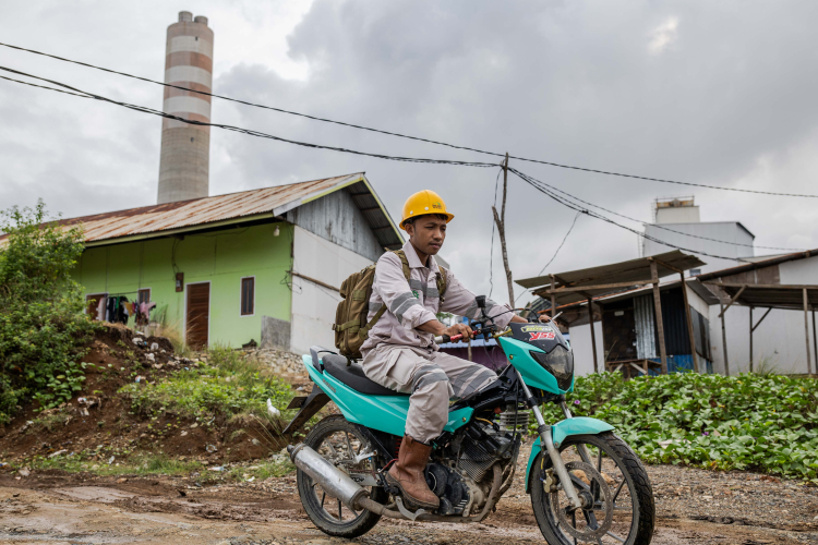 A worker using a motorcycle near a coal power plant operated by Indonesia Morowali Industrial Park (IMIP) in the villages of Labota on June 12, 2024 in Morowali, Central Sulawesi, Indonesia.