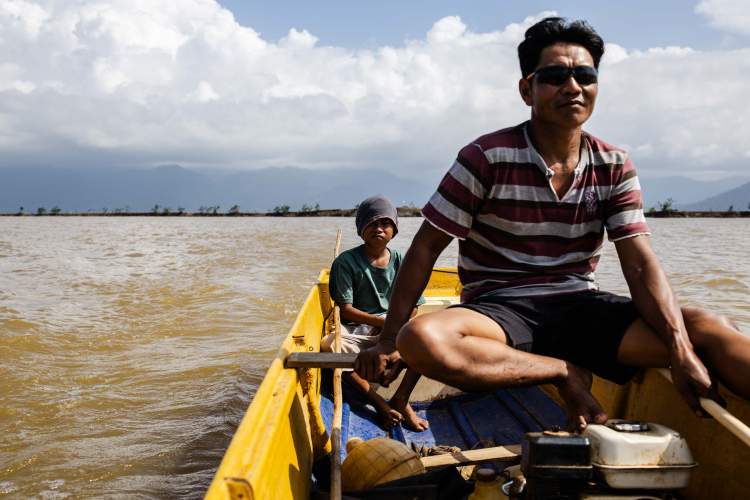 A man with his child rides on a boat through the area of sea waters contaminated by a nickel mine on June 9, 2024 in North Konawe, Southeast Sulawesi, Indonesia.