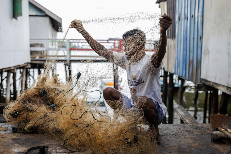 Bajau fishermen, Jusman, repair fishing nets at his house in the fishing village of Kurisa near Indonesia Morowali Industrial Park (IMIP) on June 14, 2024, in Morowali, Central Sulawesi, Indonesia.